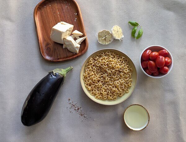 Ingredients for Anelletti alla Norma, traditional Sicilian pasta with eggplant, tomato sauce, and ricotta salata.