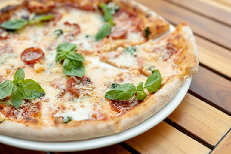 "High-angle view of a delicious Neapolitan-style pizza with spicy salami, mozzarella, tomato, and basil on a wooden table pizza diavola